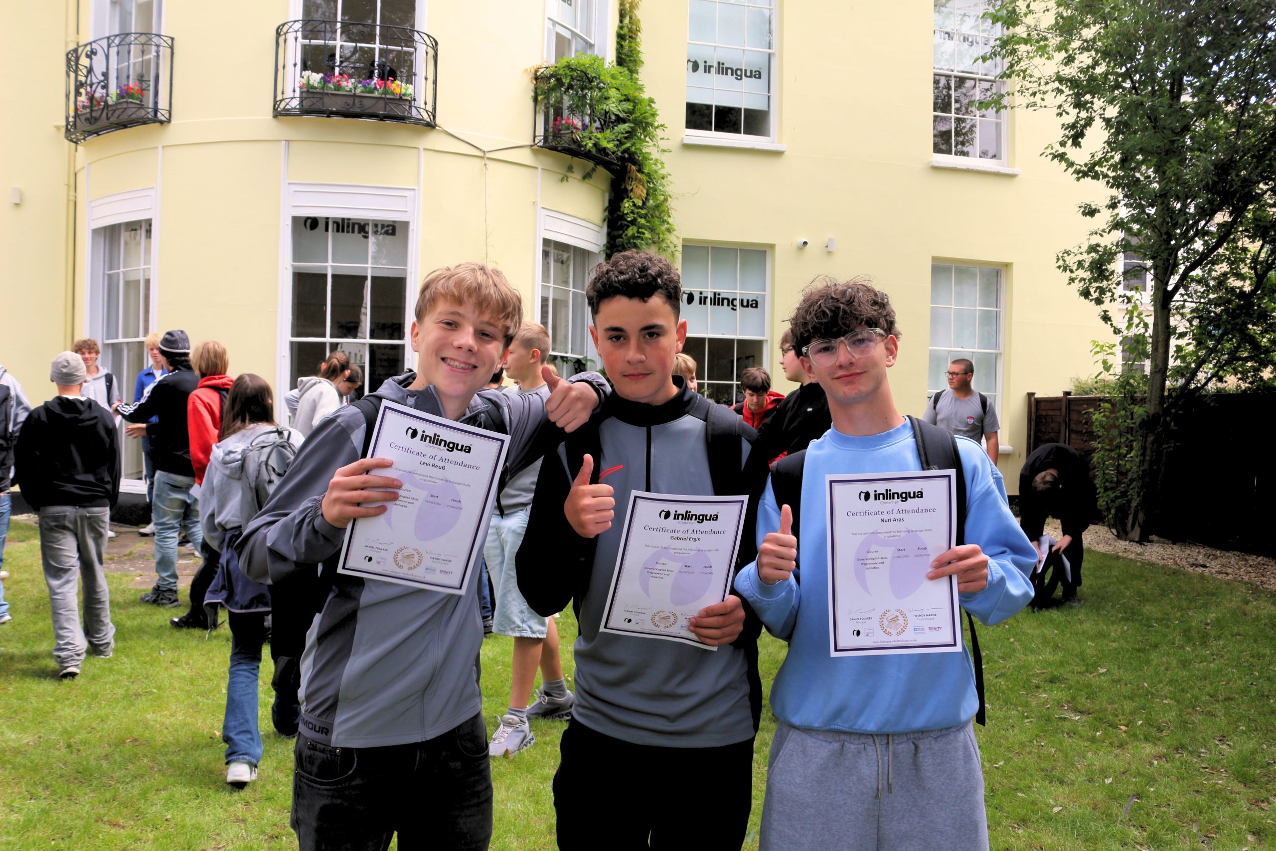 International students holding their inlingua Cheltenham certificates outside a Gloucestershire state school