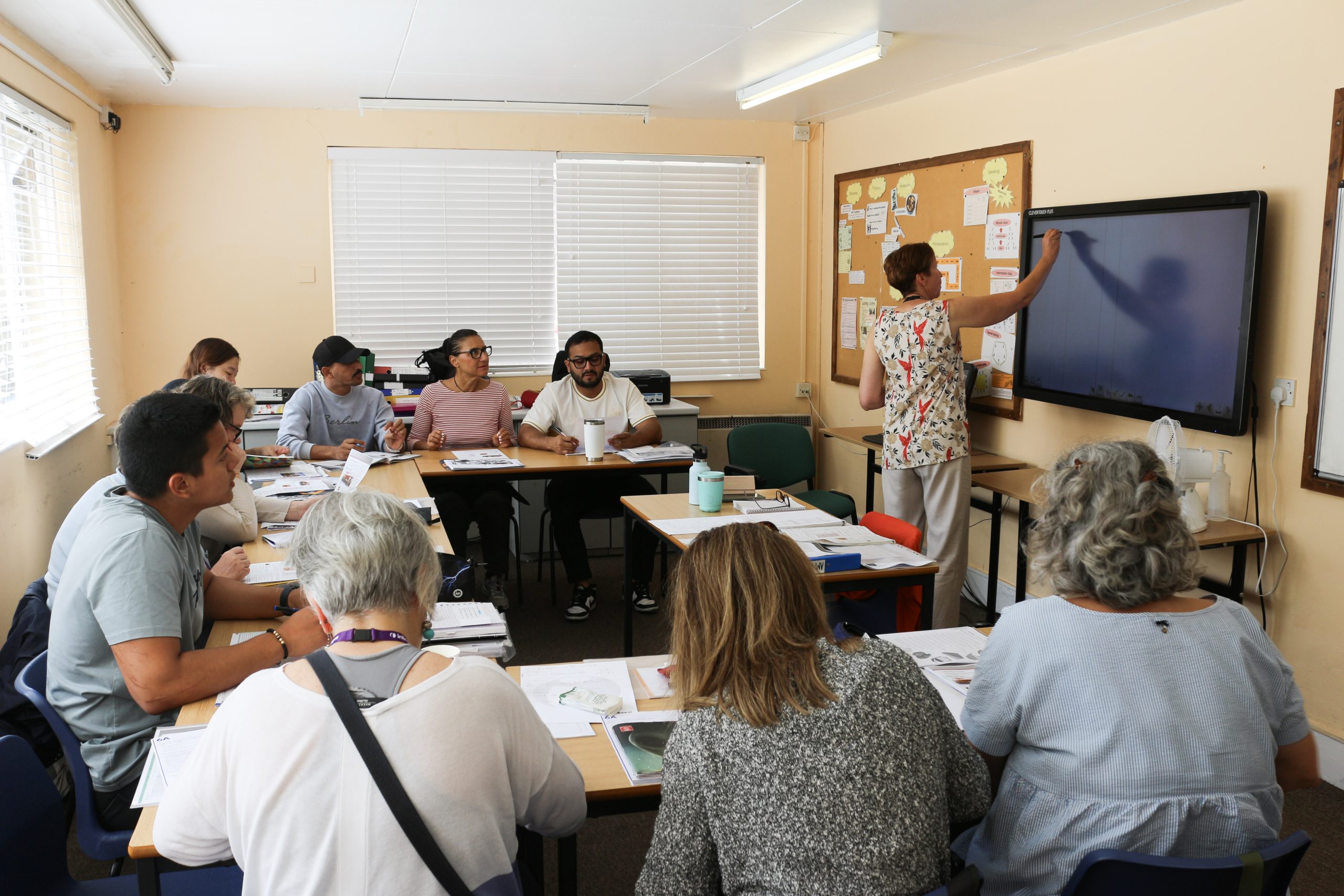 Adult international students working together with their teacher in a classroom at inlingua Cheltenham