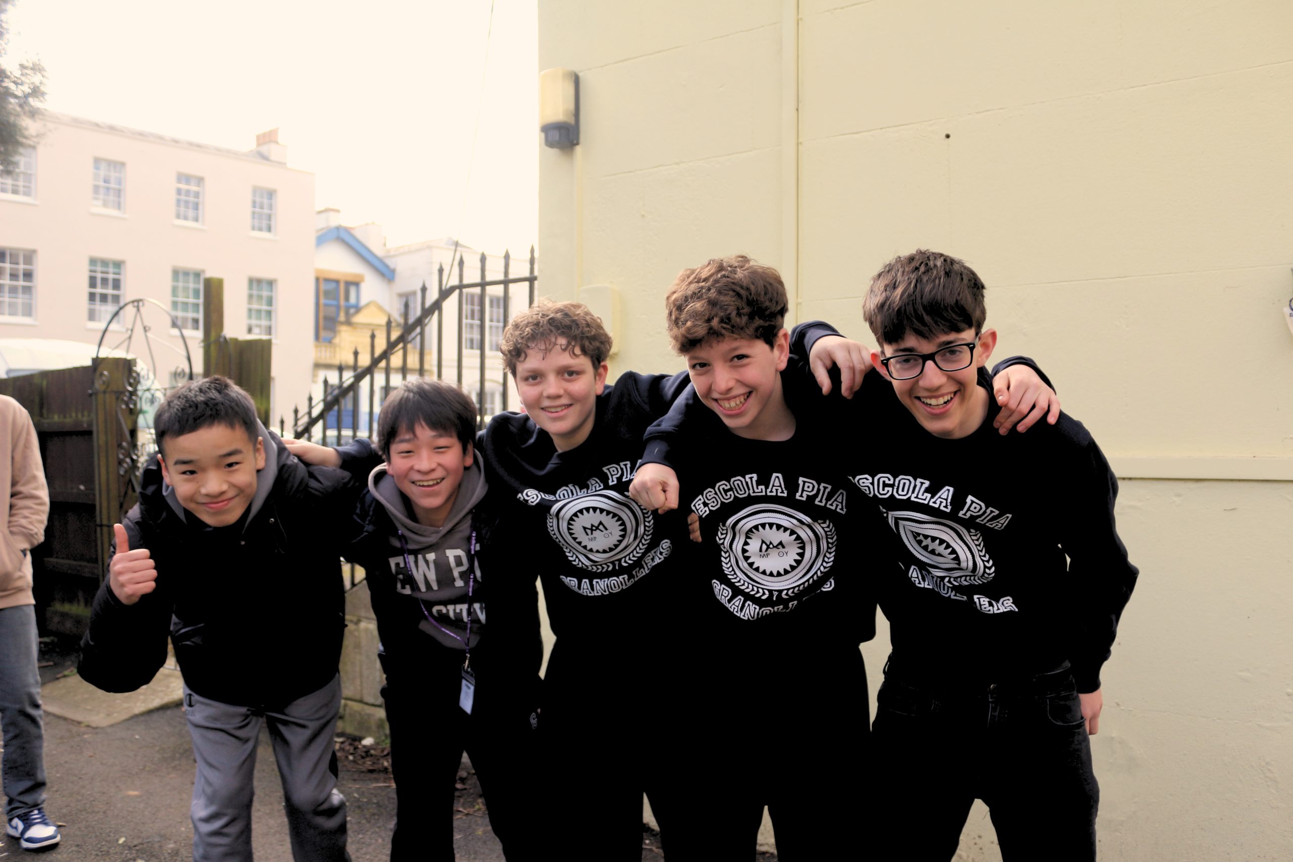 A group of teenage international students smiling together outside inlingua Cheltenham during a school holiday week