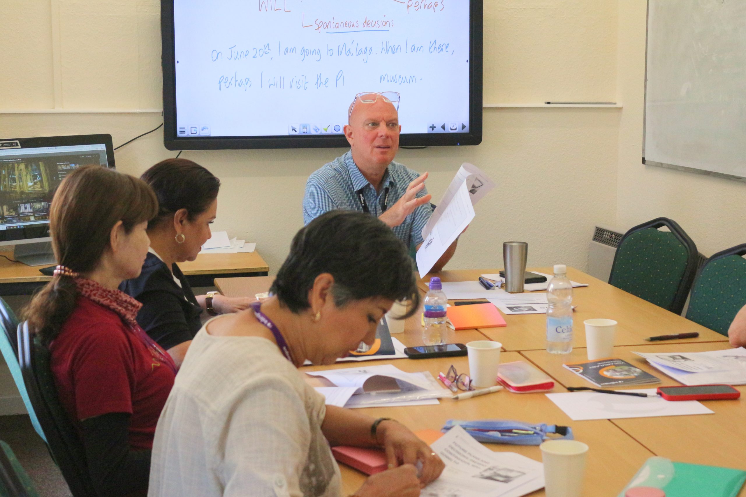 An experienced teacher working through exam technique with adult students at inlingua Cheltenham
