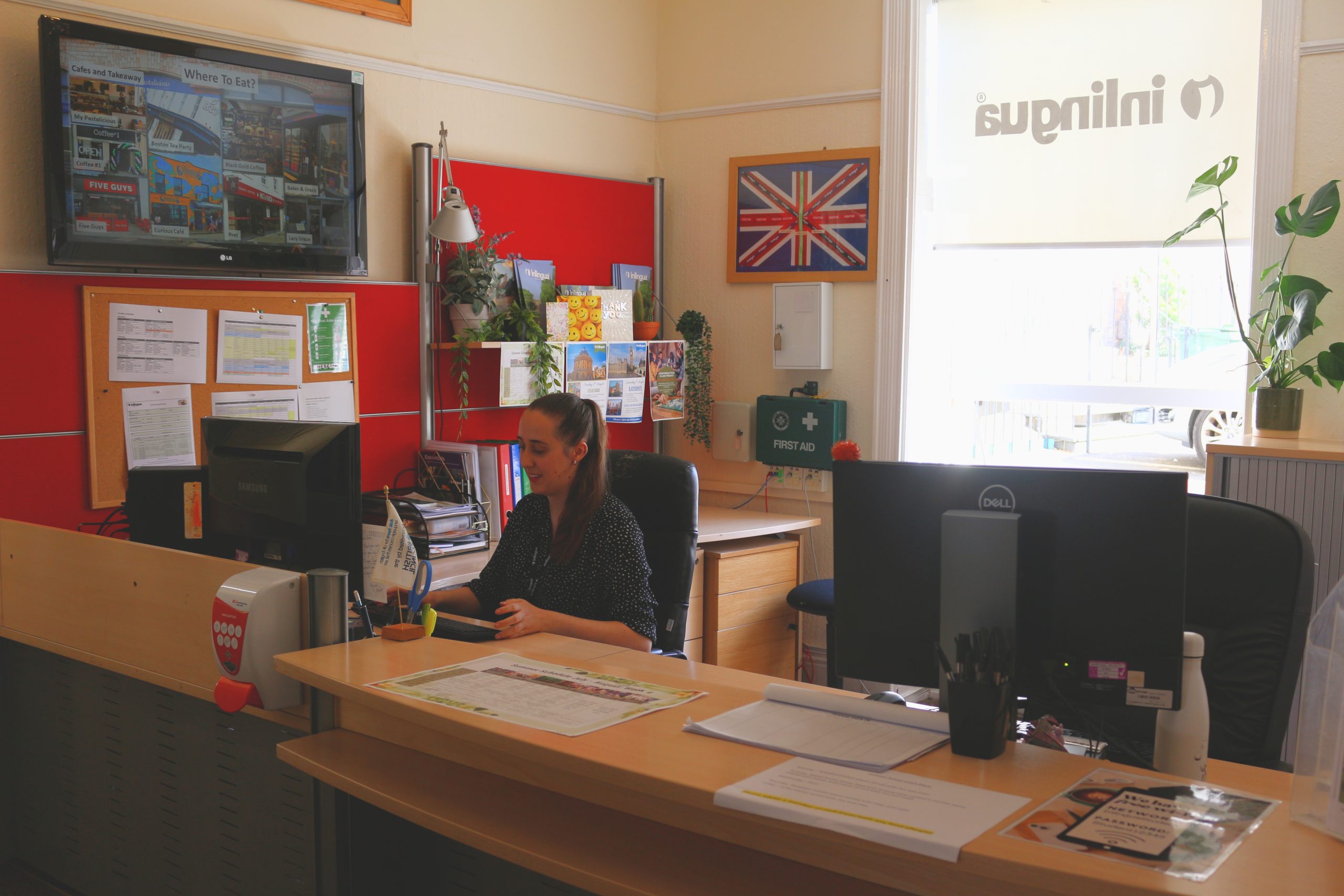 The reception desk at inlingua Cheltenham with a member of staff at work