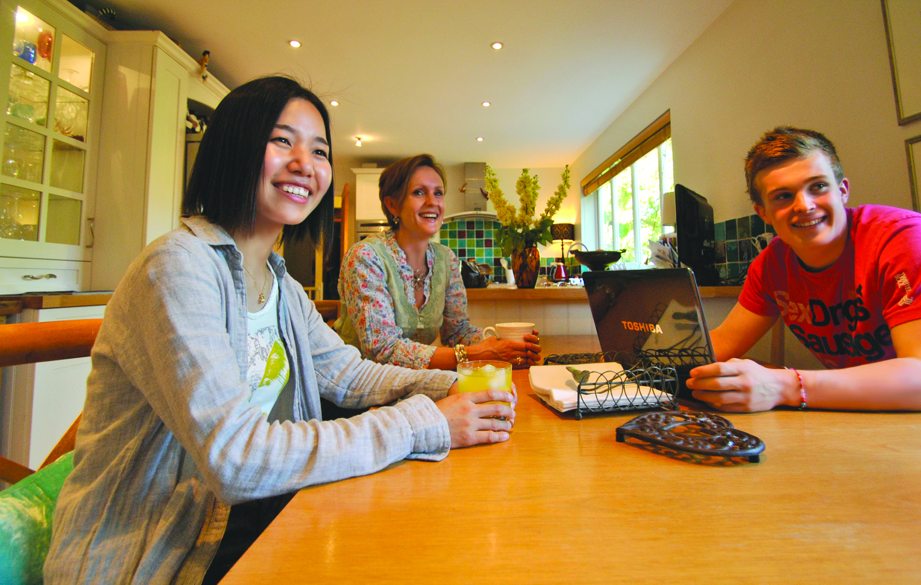 A host and an international student talking over a meal at the kitchen table of a home in Cheltenham