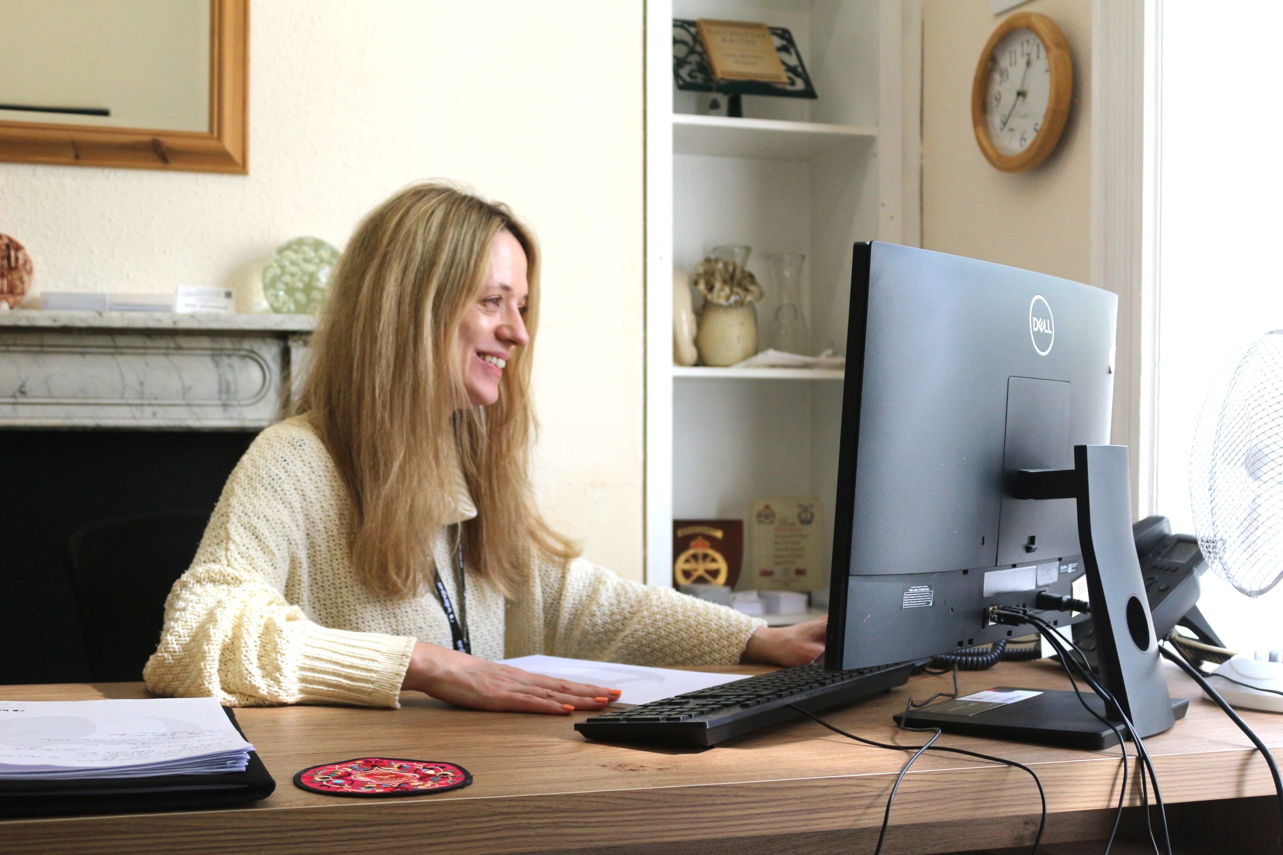 An inlingua Cheltenham teacher smiling while teaching an online English lesson at a computer